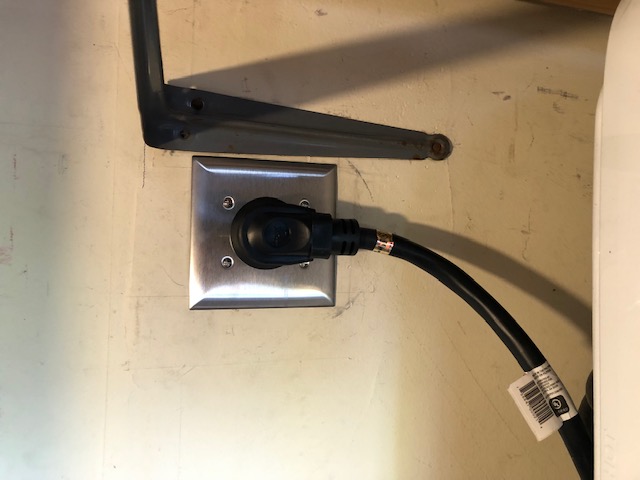 Replacement dryer receptacle, metal cover, and connected dryer cord after the documented repair